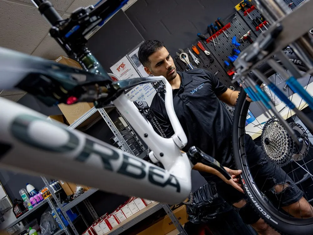 Mecánico del taller Klimaverso Bikes de Málaga ajustando una bicicleta Orbea